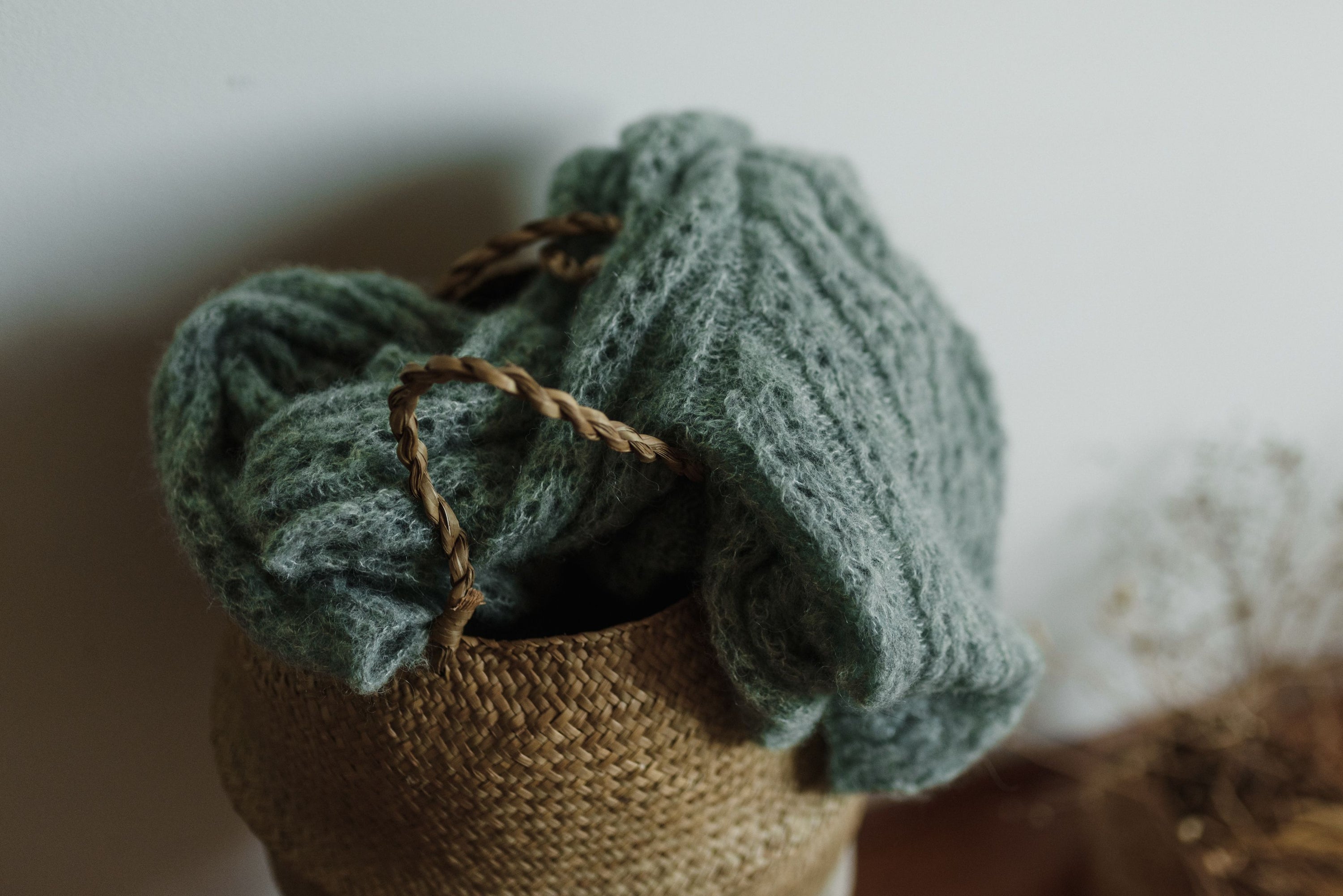 A warm, knitted woolen sweater draped elegantly inside a woven basket, perfect for cozy winter vibes.