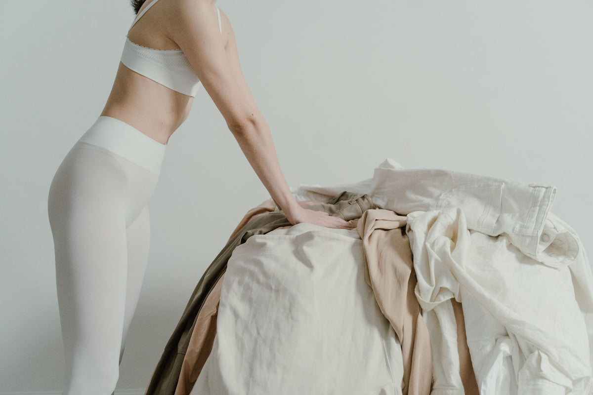 Woman sorting beige and white laundry while wearing leggings, creating a minimalistic aesthetic.